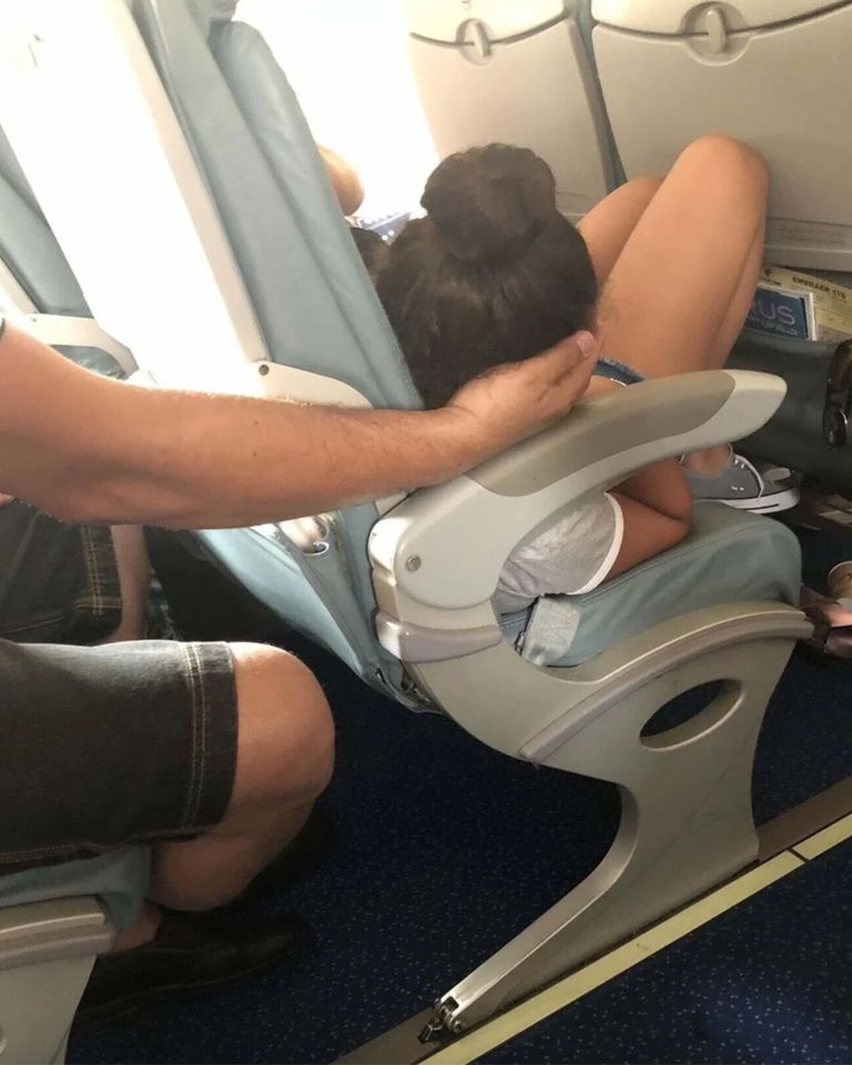 This dad cradled his daughter’s head for 45 minutes so she could sleep during a flight… but there was one detail in the picture that left the internet furiously debating 😮😮😱 See if you can spot it!