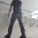 Man walks into a public washroom and uses the urinal.