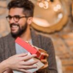 Cheerful young woman receiving a gift from her boyfriend.