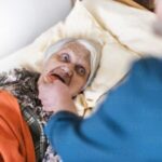 Woman taking care of old woman lying in bed