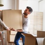 Young couple carrying big cardboard box at new home.Moving house